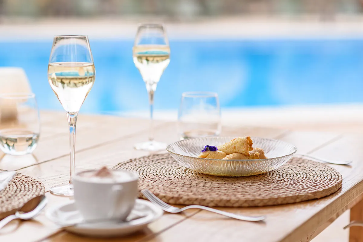 Gericht und Weingläser am Pool des Restaurants Sa Figuera